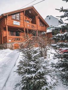 una cabaña de madera en la nieve con un árbol en Synya Gora en Bukovel