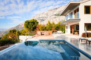 a house with a swimming pool in front of a mountain at Villa Yanko, free parking, heated pool, sea view, own children's playground, excellent facilities in Tučepi