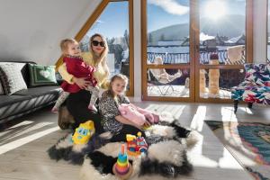 a woman and two children sitting in a living room at Bory6a Apartamenty in Zakopane