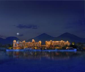 a large building in the middle of the water at night at The Leela Palace Udaipur in Udaipur