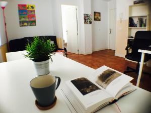a table with a book and a cup and a plant at Centro + wifi+ 2 camas de matrimonio +playa in Cádiz