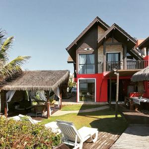 a house with a straw roof and a chair at Pousada Olhos Verdes in Bombinhas