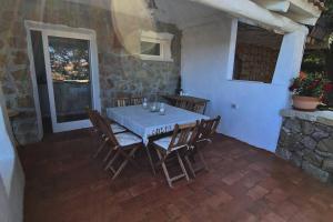 Une table à manger et des chaises sont disponibles sur la terrasse. dans l'établissement Casa Mariu' ,con giardino vista mare, à Liscia di Vacca