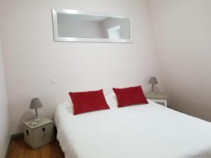 a bedroom with a white bed with two red pillows at Dreams & Love in Sarlat 1 et 2 in Sarlat-la-Canéda