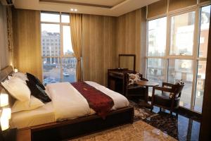 a bedroom with a bed and a desk and windows at Arto Aparthotel in Riyadh