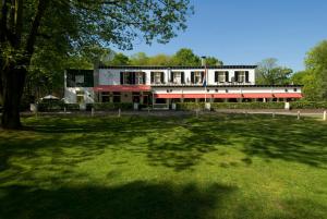 un edificio con un campo de césped delante de él en Nol in 't Bosch, en Wageningen