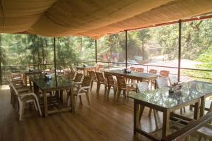 a dining room with tables and chairs and windows at Arthigamya Beach Front Resort & SPA in Gokarna