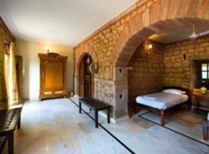 1 dormitorio con cama y pared de piedra en Chandelao Garh, en Bīnāwās