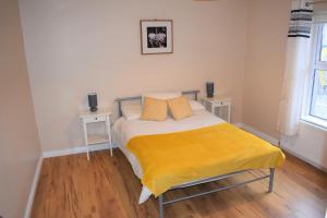 a bedroom with a bed with a yellow blanket on it at Ocean Bay in Malin