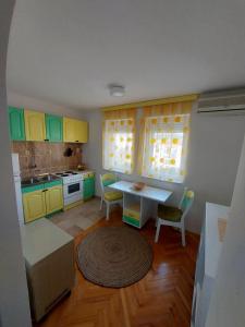 a kitchen with yellow and green cabinets and a table at Apartman Bregovi in Trebinje