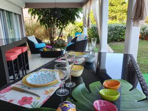 einen Tisch mit Tellern und Weingläsern auf einer Terrasse in der Unterkunft villa dans lo in Le Moule
