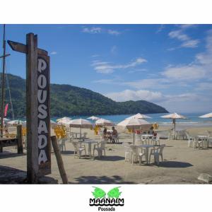 a beach with tables and chairs and umbrellas at Pousada Maanaim in Ubatuba