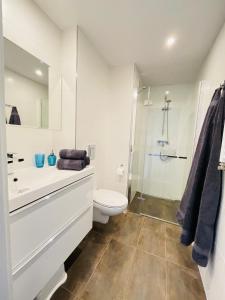 a white bathroom with a toilet and a shower at BalticSea Apartamenty in Sarbinowo