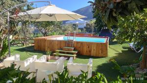 einen Pool mit einem Tisch, Stühlen und einem Sonnenschirm in der Unterkunft Siempreviva in Las Palmas de Gran Canaria