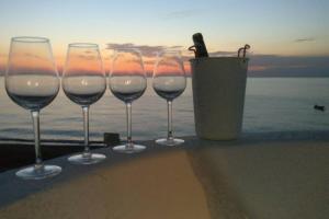 un grupo de copas de vino sentado en una mesa cerca del océano en Il Giglio di mare, en San Saba