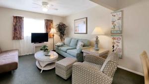 a living room with a couch and a tv at Carlton House Motel and Suites in St. Pete Beach