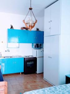 una cocina con armarios azules y una lámpara de araña en Yacht Front Studio - No 3, en Ios Chora