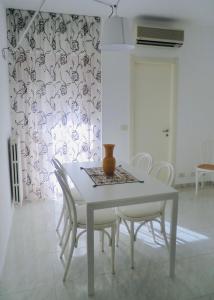 Casa Nica في موديكا: طاولة طعام مع كراسي بيضاء و مزهرية عليها