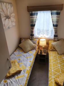 two twin beds in a room with a window at Relaxing Breaks with Hot tub at Tattershal lakes 3 Bedroom in Tattershall +27 photos