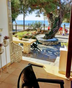 un patio con una mesa, un árbol y el océano en Aegialis, en Skala Kallirakhis