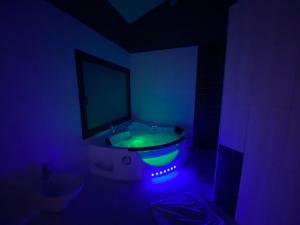 een donkere badkamer met een bad met groen licht bij Le Jas de Joucas Hôtel-Restaurant in Joucas
