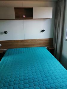 a bedroom with a bed with a blue comforter at Les dunes de contis in Saint-Julien-en-Born