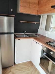a kitchen with white cabinets and a stainless steel refrigerator at Les dunes de contis in Saint-Julien-en-Born