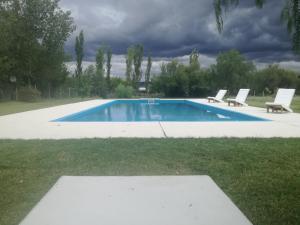 una piscina con due sedie a sdraio in erba di Tardecitas del Atuel a Rama Caída
