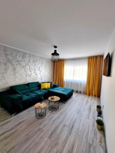 uma sala de estar com um sofá verde e duas mesas em Apartament Central Iulia em Sibiu