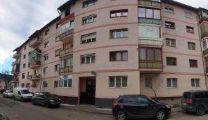a large pink building with cars parked in front of it at Apartament Central Iulia in Sibiu