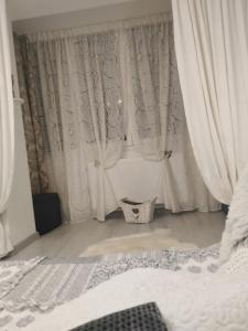 1 dormitorio con cortinas blancas y 1 cama en La Monica 2 - Cazare Straja - Lupeni - Retezat - Parang, en Lupeni
