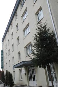a large white building with a tree in front of it at Hotel Merkur in Miercurea-Ciuc