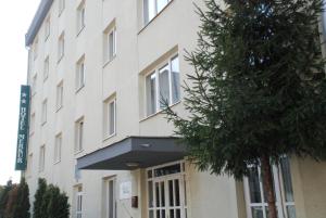 a building with a tree in front of it at Hotel Merkur in Miercurea-Ciuc