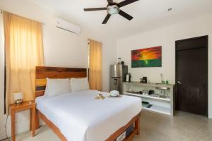 a bedroom with a large white bed with a ceiling fan at Los Amigos Tulum in Tulum