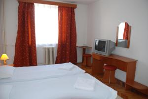 a hotel room with a bed and a tv on a desk at Hotel Merkur in Miercurea-Ciuc