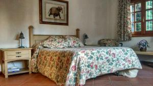 a bedroom with a bed and a nightstand with a bedspread at La Casita de Chozas in Soto del Real