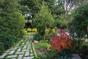 a brick path in a garden with trees and bushes at La Casita de Chozas in Soto Real