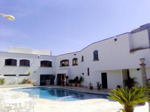 a villa with a swimming pool in front of a building at Hotel Del Parque in Tequisquiapan
