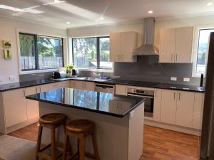 a kitchen with white cabinets and a black counter top at Kurow House on Bledisloe - A2O Cycle Trail Oasis. in Kurow