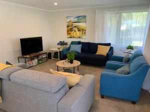 a living room with blue couches and a tv at Kurow House on Bledisloe - A2O Cycle Trail Oasis. in Kurow