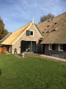 een groot bakstenen huis met een rieten dak bij De Rheezer Kamer in Hardenberg