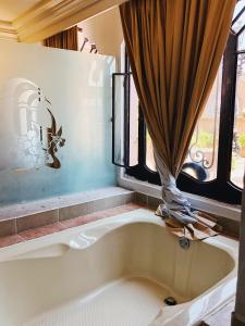 y baño con bañera y ventana. en Hotel Casa de los Angel's en San Juan de los Lagos