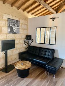 a living room with a black leather couch and a tv at Lou Mirèio in Aigues-Mortes