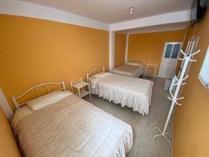 twee bedden in een kamer met gele muren bij Hostal CASABLANCA in Oruro