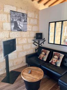 a living room with a black couch and a tv at Lou Mirèio in Aigues-Mortes
