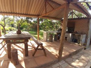 a patio with a wooden table and a table and a bench at Pousada Natureza in São Thomé das Letras
