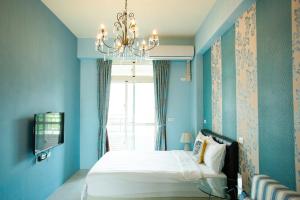 Dormitorio azul con cama y lámpara de araña en Brownbnb, en Chishang