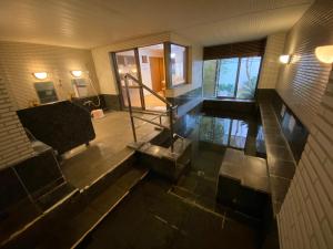 - une piscine intérieure dans une maison avec de l'eau au sol dans l'établissement Atami Onsen Guest House Megumi, à Atami