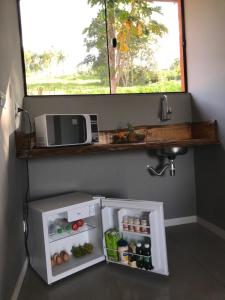 a small refrigerator in a kitchen with a microwave at Rancho dos Pássaros Amarelos in Campestre