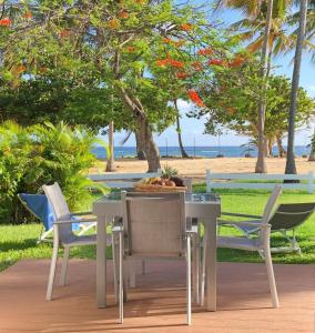 una mesa y sillas en un patio con vistas a la playa en Beautiful Ground Floor, Seaside Studio Flat, en Le Moule